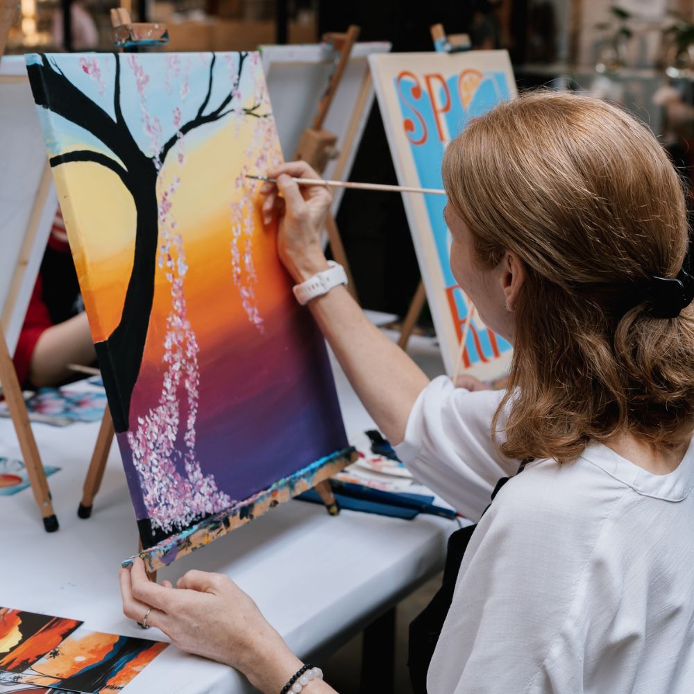 Žena maľuje západ slnka v kurze maľovania ArtMoment